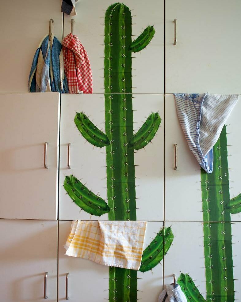 Küchenschränke mit einem aufgedruckten Kaktus und Handtüchern, die über einzelne Türen gehängt wurden