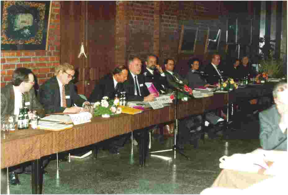Ein Foto von einer Konferenz: mehrere Personen sitzen in Tischreihen, an den Tischen stehen Mikrofone.