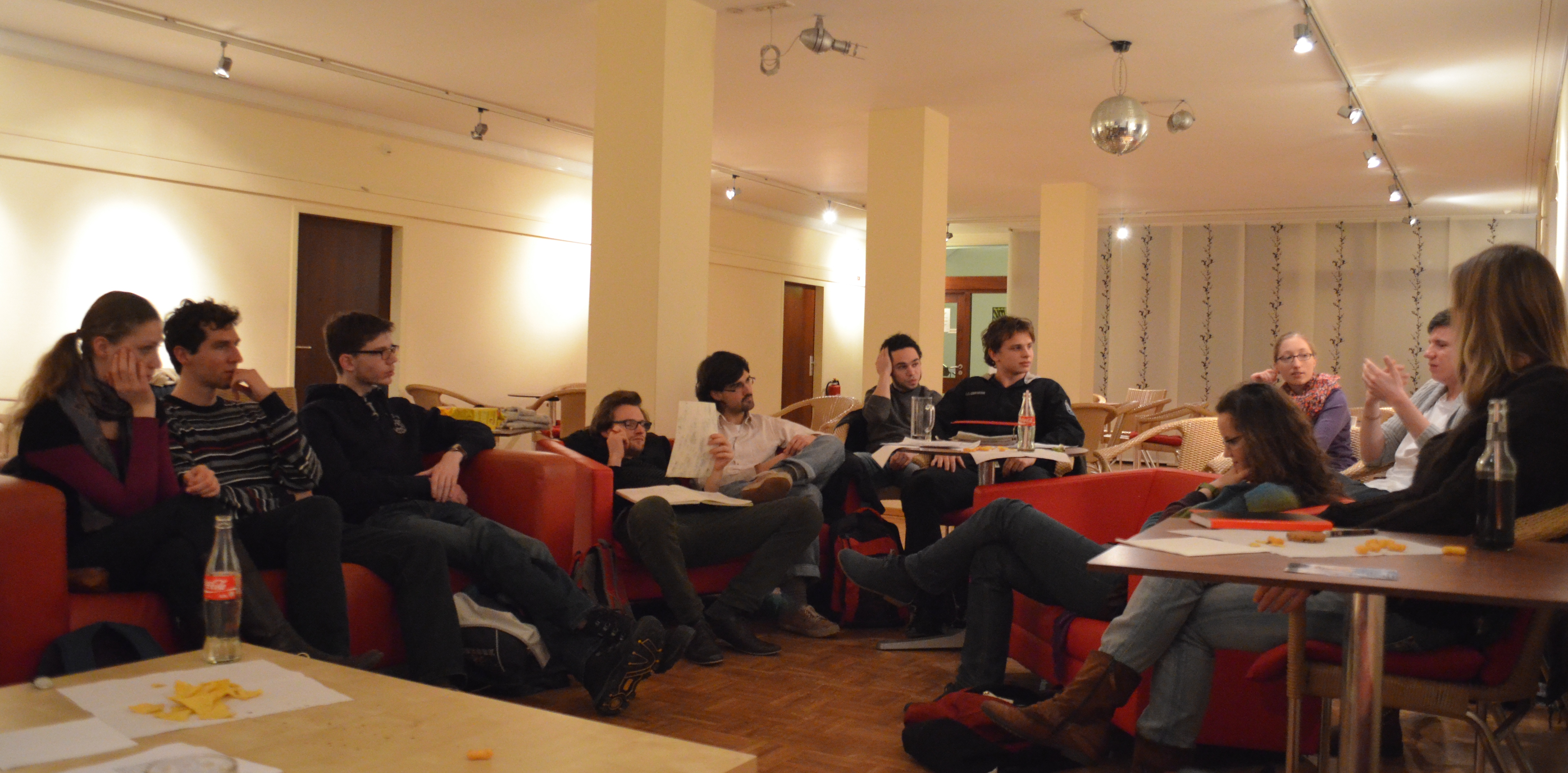 Mehrere Studierende sitzen auf Sofas in einem Kreis und diskutieren intensiv über etwas.
