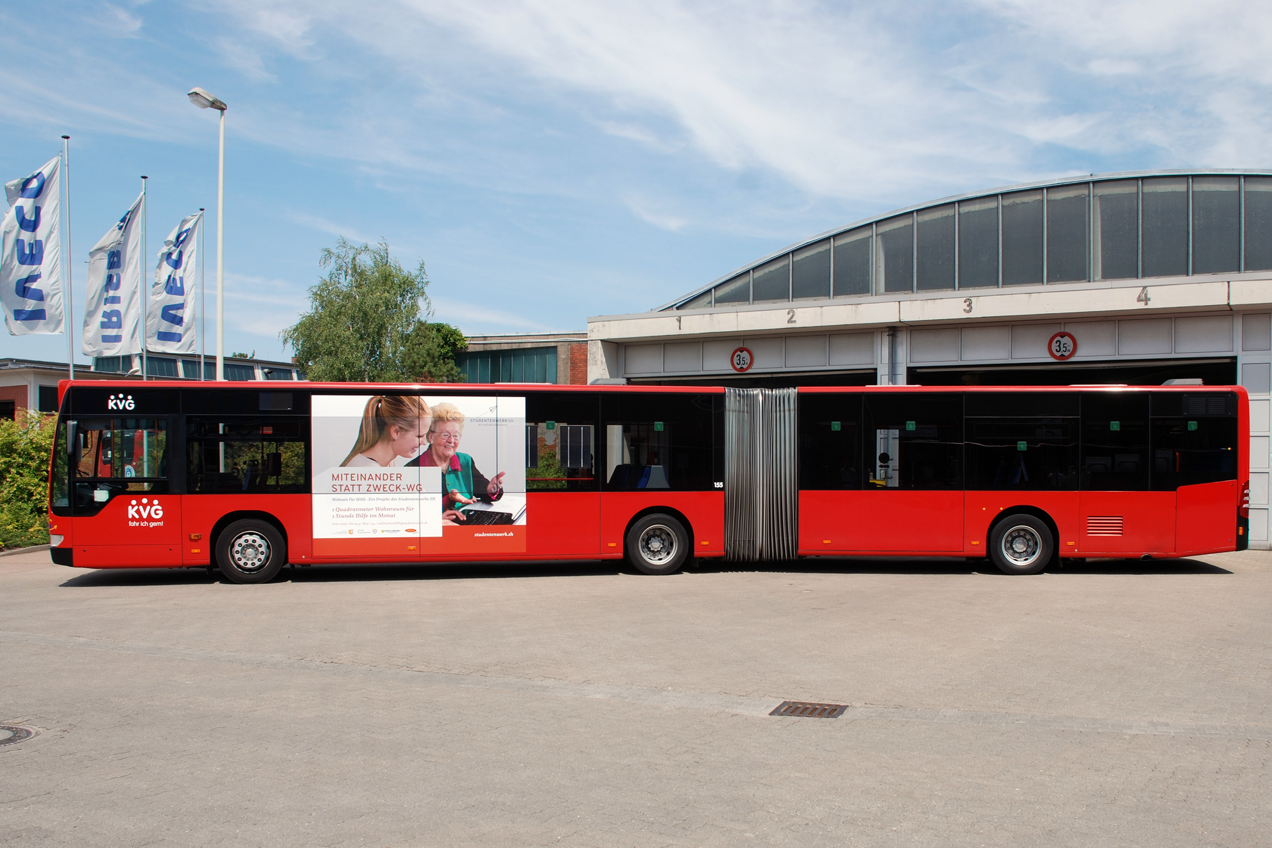 Ein großformatiges „Traffic Board“ auf einem Bus mit einem Bild von jüngeren und einer älteren Dame und mit der Unterschrift "Miteinander statt Zweck-WG".