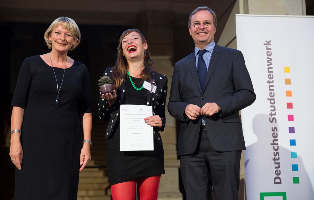 In einer Reihe auf der Bühne stehen DSW-Vizepräsidentin Andrea Klug, die fröhlich lachende Gewinnerin des Plakatwettbewerbs Xueh Magrini Troll und Thomas Rachel.