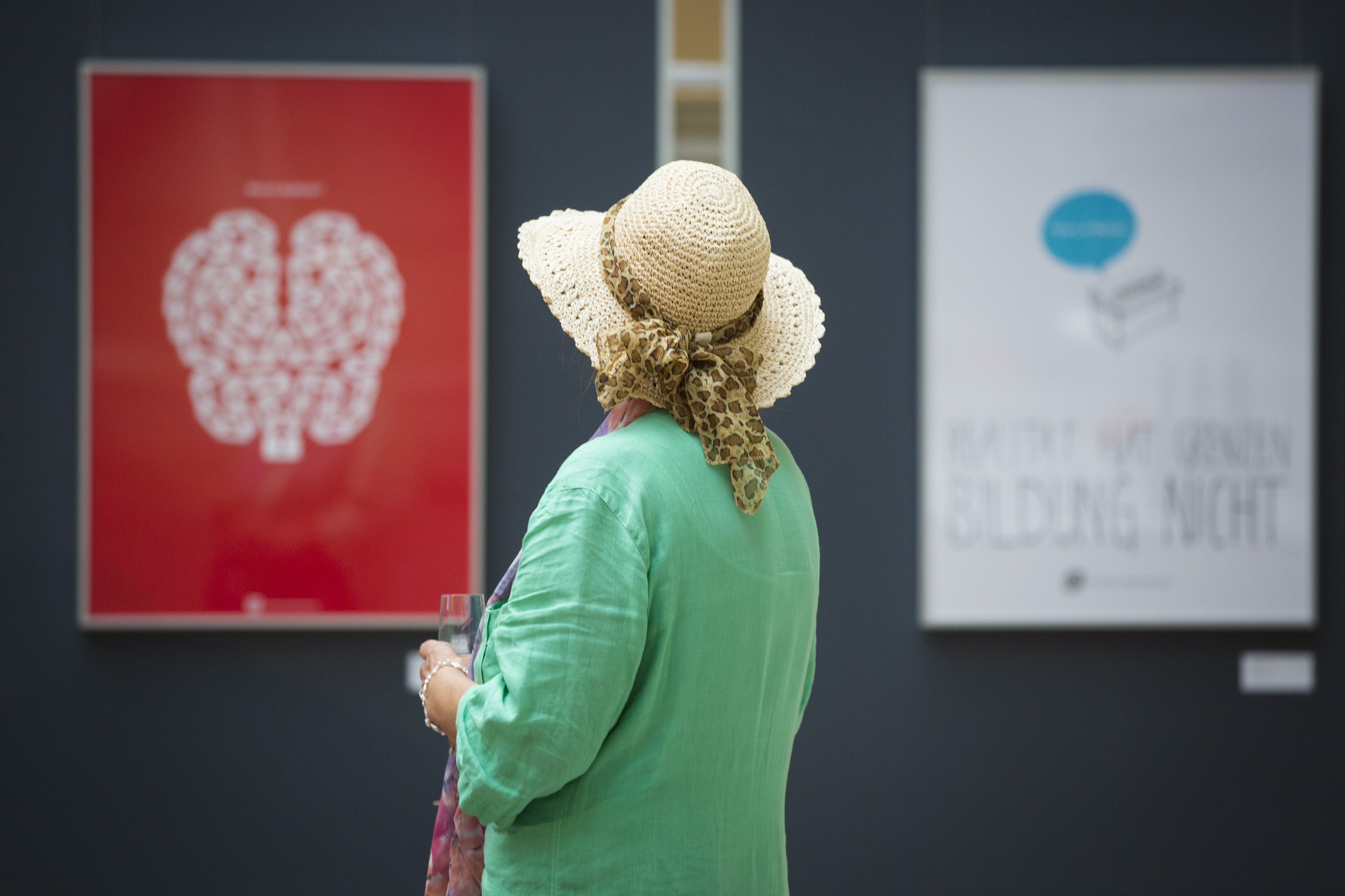 Eine Frau mit Strohhut beim betrachten zweier ausgestellter Plakate.  | (c) Kay Herschelmann
